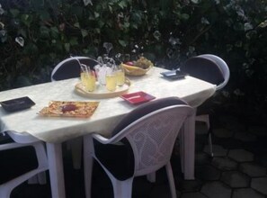 Un espacio de comedor al aire libre con una mesa lista para dos, que incluye un plato de comida y bebidas.