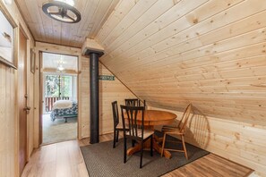 A wooden interior with a dining table and chairs, a black column, and a door leading to a balcony. - Rugers Retreat | Fire Pit | Grill | 35 Mins To YNP (Island Park)