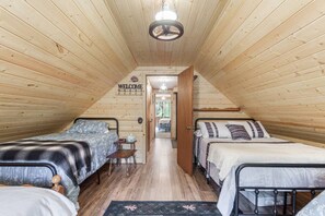 A cozy cabin with two beds, a small table, and a 'WELCOME' sign. - Rugers Retreat | Fire Pit | Grill | 35 Mins To YNP (Island Park)