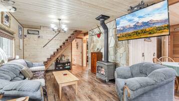 Een gezellig interieur van een chalet met een open haard, houten vloeren en een groot raam met uitzicht op de bergen.