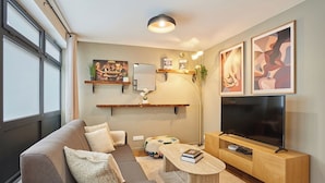Ein modernes Wohnzimmer mit Sofa, Couchtisch, Fernseher und Kunstwerken.