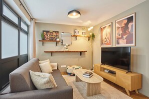 A modern living room with a sofa, coffee table, TV, and artwork. - Superb apartment Center of Paris (Paris)