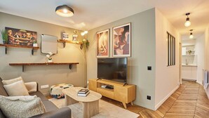 Ein modernes Wohnzimmer mit Sofa, Couchtisch, Fernseher und Bildern an der Wand.