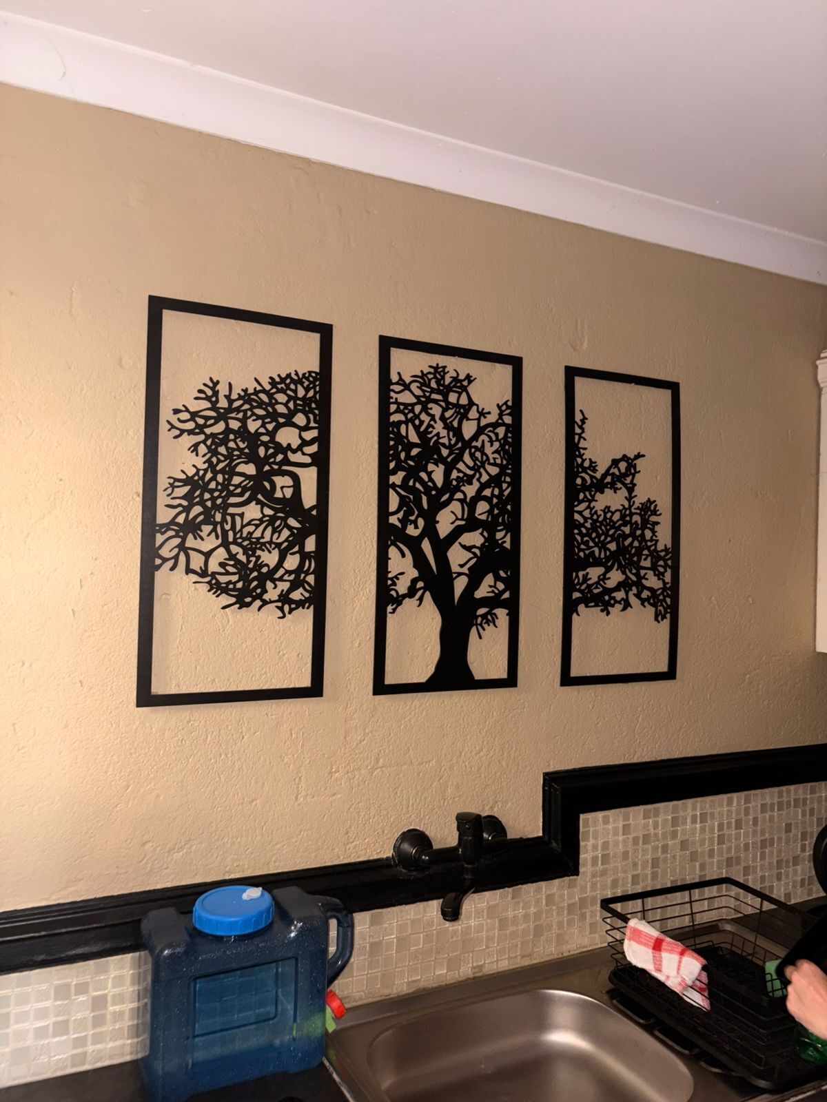 Eine Küche mit Spüle, Geschirrgestell und drei an der Wand befestigten Baumkonturen.