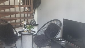 A modern living room with a spiral staircase, black chairs, a TV stand, and a small table with decorative items. - Stylish Private Retreat Sleeps 3 Secure Work-Friendly Unique Design Stay (Johannesburg)
