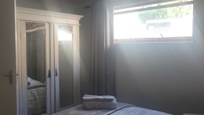 A bedroom with a bed, a wardrobe, a window with curtains, and a sign on the wall. - Stylish Private Retreat Sleeps 3 Secure Work-Friendly Unique Design Stay (Johannesburg)