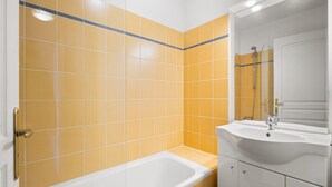 A bathroom with yellow tiles, a white bathtub, and a sink with a mirror. - Chic Light-Filled Pool Oasis in Grasse (Grasse)