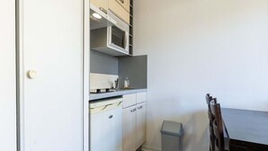 Een kleine keuken met een magnetron, vaatwasser en een prullenbak.