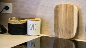 Een keukenblad met een koffiezetapparaat, een houten snijplank en een geweven mand.