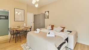 Ein Hotelzimmer mit Bett, Nachttisch, Essecke mit Stühlen, Mikrowelle und einer Tür.