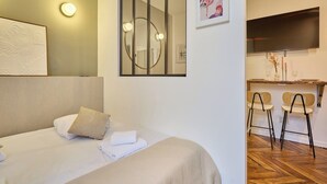Une chambre d’hôtel comprenant un lit, un bureau avec deux chaises, une télévision et un miroir avec éclairage.