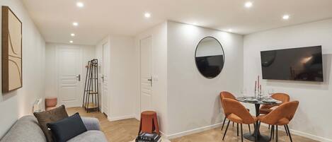 Un salon moderne avec un canapé, une table à manger et des chaises, un téléviseur et un tableau accroché au mur.