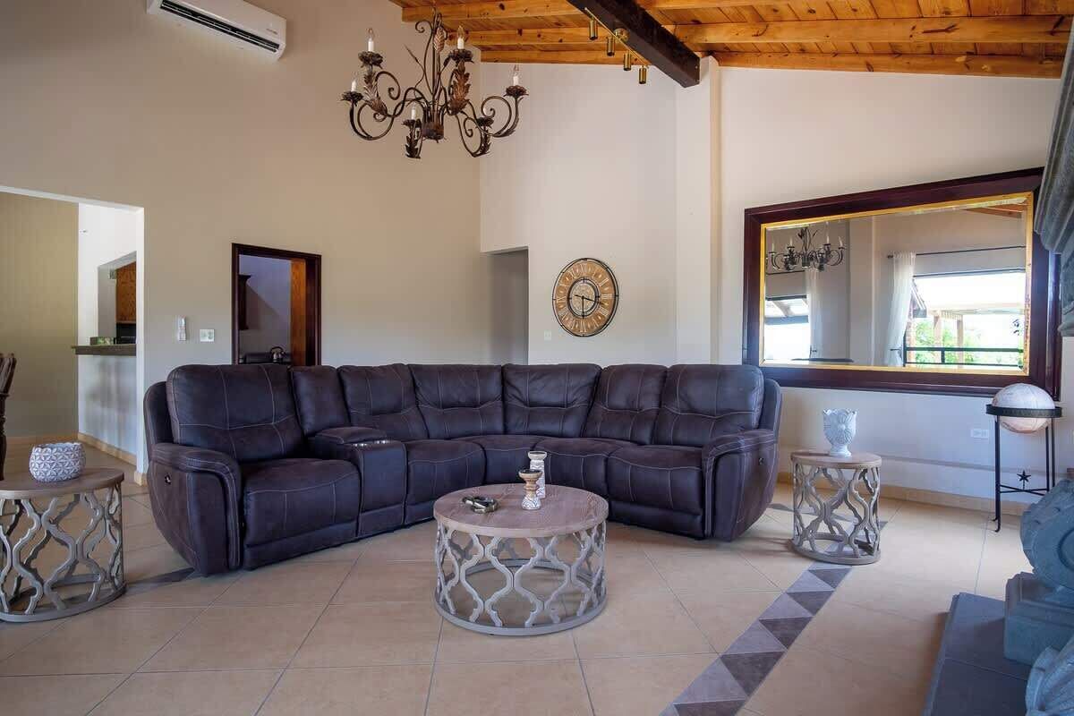 A living room with a sectional sofa, a round coffee table, a chandelier, and a large mirror.