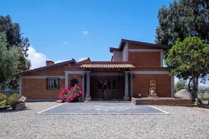 Una casa a due piani con facciata in mattoni, tetto in tegole e un ingresso principale con porta e finestre.