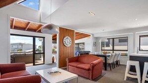 Ein modernes Wohnzimmer mit einer Couch, einem Couchtisch und einem Essbereich mit Stühlen und einem Tisch.