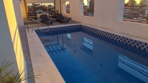 A rooftop pool with clear blue water, a pergola, and a city view. - Paranainn Hotel Asuncion (Asunción)