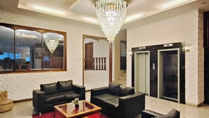 A modern living room with a chandelier, leather sofas, a red rug, and a glass coffee table. - Paranainn Hotel Asuncion (Asunción)