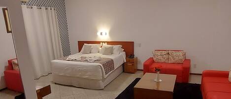 Una habitación de hotel moderna con una cama, un sofá rojo, una mesita y un patrón de pared a cuadros.