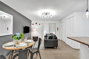 Un espace repas moderne avec une table ronde, des chaises, une plante en pot et un téléviseur.