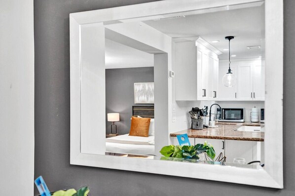 Une chambre moderne équipée d’un lit, d’une table de chevet, d’une lampe et d’un coin cuisine comprenant des placards, un four à micro-ondes et un évier.