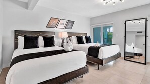 A hotel room with two beds, a large mirror, and a ceiling light fixture.