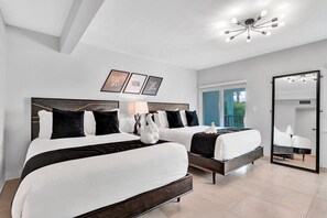 Une chambre d’hôtel avec deux lits, un grand miroir et un luminaire au plafond.