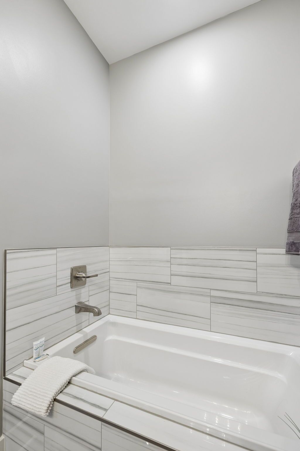 Ein modernes Badezimmer mit einer weißen Badewanne, einem Handtuch und einer Duschkabine.