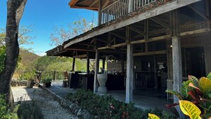 A wooden building with a balcony, outdoor seating, and a stone wall.