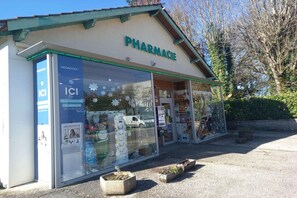 A pharmacy with a large glass window, a sign reading 'PHARMACIE,' and a small outdoor seating area with planters. - Retro House Near Rocamadour & Padirac (ALVIGNAC)