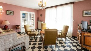 Una stanza con pavimento a scacchi, un lampadario, una televisione e una finestra con tende.