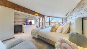 Un dormitorio con cama, televisor, ventana con vistas y techo de madera.