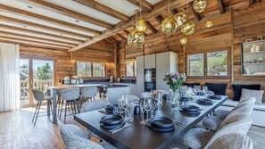 Ein modernes Blockhaus-Interieur mit Essbereich, Küche und großen Fenstern mit Blick ins Freie.