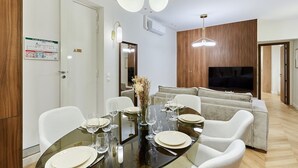 A dining area with a glass table set for six, white chairs, and a modern chandelier. - Beautiful apartment with AC - Center of Paris (Paris)