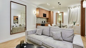 A modern living room with a grey sofa, wooden cabinets, a dining area, and a large mirror. - Beautiful apartment with AC - Center of Paris (Paris)
