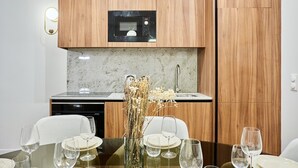 A modern kitchen with wooden cabinets, a built-in microwave, and a dining table set for four with wine glasses and plates. - Beautiful apartment with AC - Center of Paris (Paris)