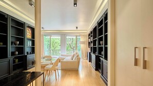 A modern kitchen with a marble countertop, a dining area with a white sofa, and a view of greenery outside. - Superb 2 bdr apartment Terrace Neuilly-sur-Seine (Neuilly-sur-Seine)