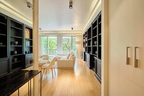 A modern kitchen with a marble countertop, a dining area with a white sofa, and a view of greenery outside. - Superb 2 bdr apartment Terrace Neuilly-sur-Seine (Neuilly-sur-Seine)