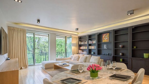 A modern living room with a sofa, a dining table set for six, and a bookshelf. - Superb 2 bdr apartment Terrace Neuilly-sur-Seine (Neuilly-sur-Seine)