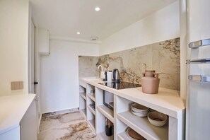 A narrow kitchen with white cabinetry, a marble backsplash, and a built-in oven. - Charming AC Duplex - Bastille Le Marais (Paris)