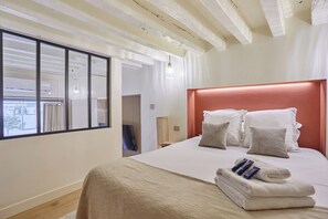A modern hotel room with a large bed, a view through a window, and a wooden ceiling. - Charming AC Duplex - Bastille Le Marais (Paris)