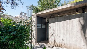 Une structure en béton dotée d’une porte, entourée de verdure.