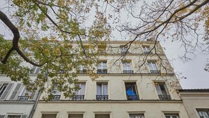 A multi-story building with balconies, windows, and a tree in the foreground. - Beautiful renovated apartment with AC - Paris East (Paris)