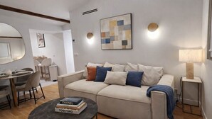A modern living room with a sofa, a coffee table, a dining area with chairs, and a lamp. - Beautiful renovated apartment with AC - Paris East (Paris)
