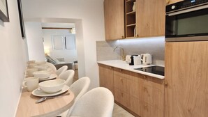A modern kitchen with wooden cabinets, a built-in oven, and a dining area with a table and chairs. - Beautiful renovated apartment with AC - Paris East (Paris)