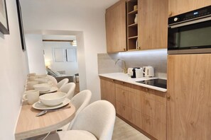 A modern kitchen with wooden cabinets, a built-in oven, and a dining area with a table and chairs. - Beautiful renovated apartment with AC - Paris East (Paris)