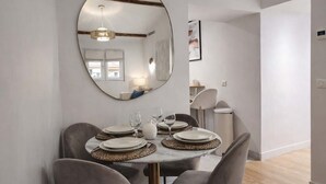 A dining area with a round table, grey chairs, and a large mirror on the wall. - Beautiful renovated apartment with AC - Paris East (Paris)