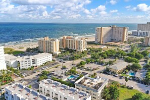 A coastal hotel area with multiple buildings, a parking lot, and a beach in the background. - Stylish 1BR Suite w/ Pool & Steps to the Beach (Pompano Beach)