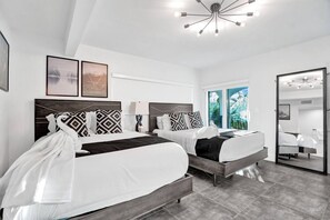 A modern hotel room with two beds, a large window, a ceiling light fixture, and a mirror. - Stylish 1BR Suite w/ Pool & Steps to the Beach (Pompano Beach)