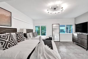 Habitación de hotel moderna con una cama grande, televisión, cómoda y balcón con vistas.