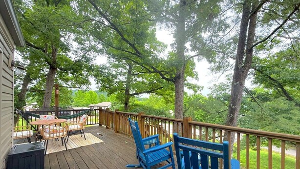 A wooden deck with outdoor furniture, including chairs and a table. - The Sunset Perch | Pet-Friendly + Deck (Eureka Springs)